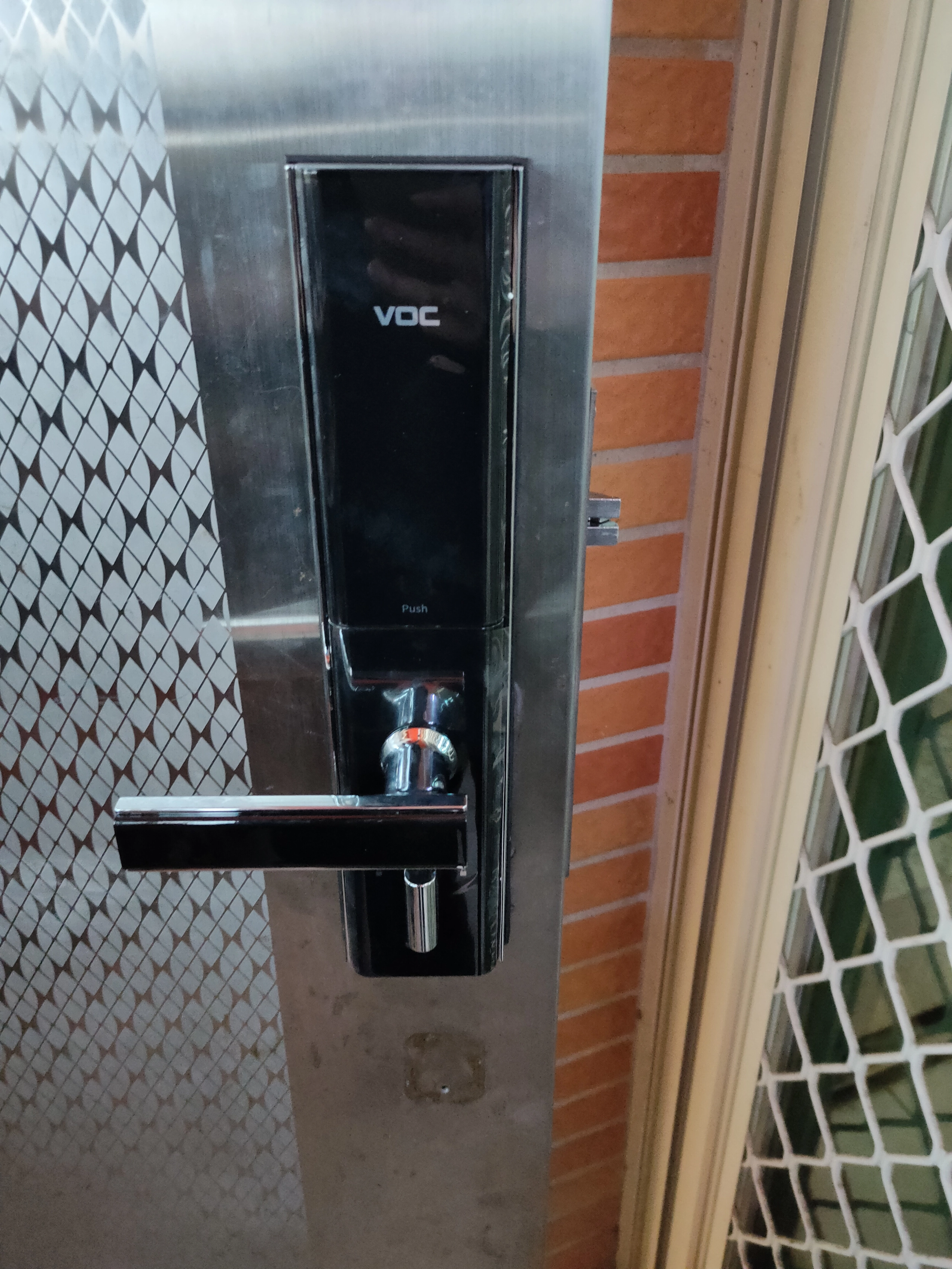 白鐵門黑色密碼電子鎖與紅磚牆
